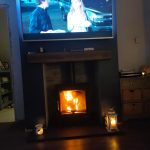 Roaring Fireplaces Installations wood burning stove with TV above.