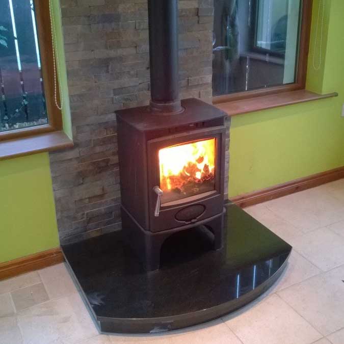Roaring Fireplaces Installations wood burning stove on black marble hearth